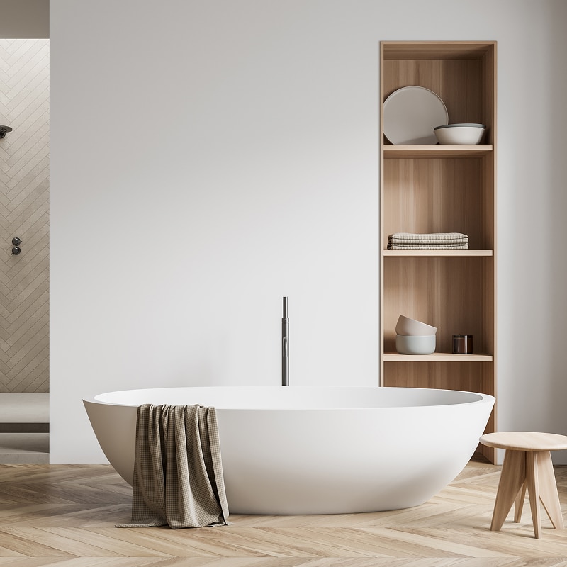 Baignoire îlot blanche moderne dans salle de bain design épurée. Parquet clair, étagère bois et douche carrelée.